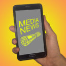 Photoillustration of a hand holding a phone with Media News on it.